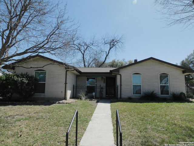 ranch-style home featuring a front yard, fence, and brick siding