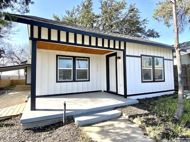 exterior space featuring covered porch, board and batten siding, and fence