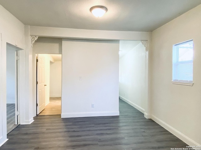 empty room with dark wood-style floors and baseboards