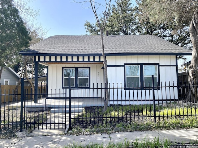 view of front of property featuring a fenced front yard, a gate, a shingled roof, and board and batten siding