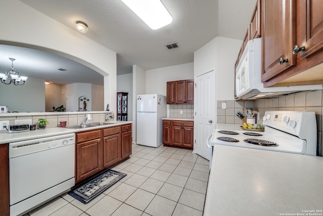 kitchen featuring white appliances, light countertops, a sink, and brown cabinetry