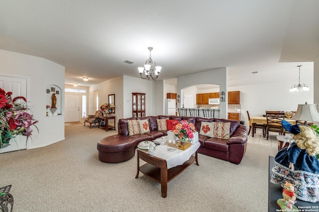 living area featuring arched walkways, light colored carpet, a notable chandelier, and visible vents