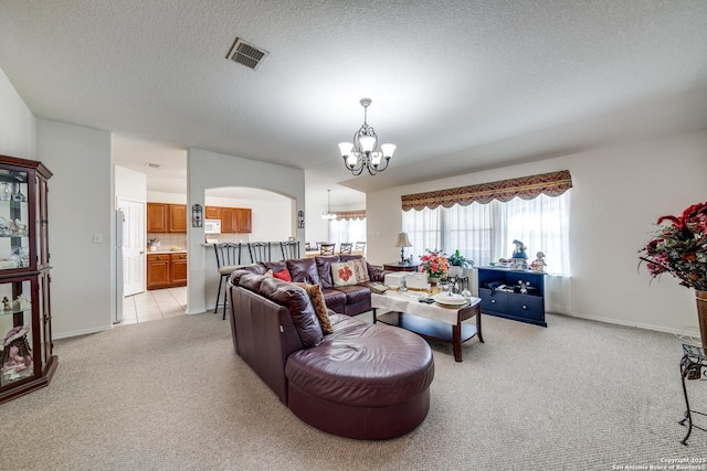 living room with arched walkways, light colored carpet, visible vents, a textured ceiling, and a chandelier