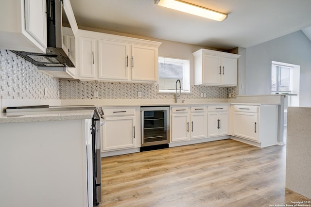 kitchen featuring beverage cooler, white cabinets, a peninsula, stainless steel electric stove, and light countertops