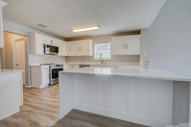 kitchen with stainless steel appliances, white cabinets, visible vents, and backsplash