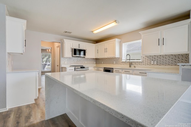 kitchen featuring stainless steel appliances, a healthy amount of sunlight, visible vents, and decorative backsplash