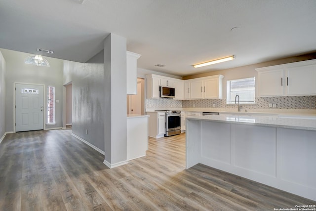 kitchen with stainless steel appliances, visible vents, light countertops, backsplash, and white cabinets