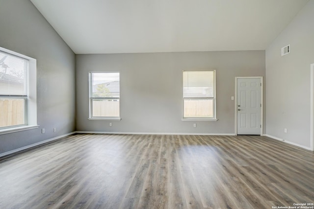 spare room featuring high vaulted ceiling, baseboards, visible vents, and wood finished floors