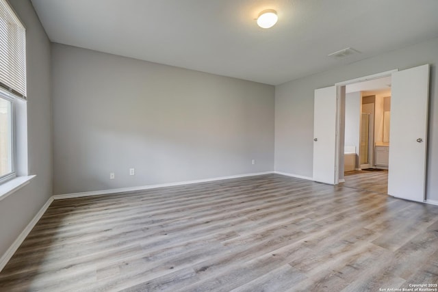 spare room with visible vents, baseboards, and wood finished floors