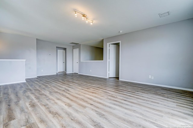 empty room featuring visible vents, baseboards, and wood finished floors