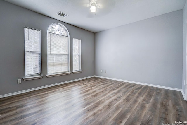 empty room with baseboards, visible vents, and wood finished floors