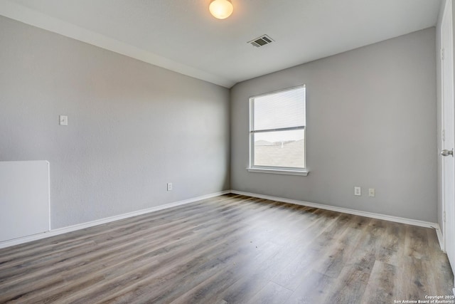 spare room with visible vents, baseboards, and wood finished floors