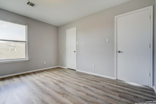 unfurnished room featuring wood finished floors, visible vents, and baseboards