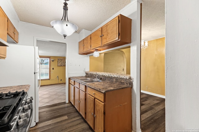 kitchen featuring stainless steel gas range, a textured ceiling, dark wood-style flooring, and a sink