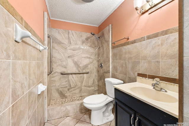 bathroom with tile walls, toilet, a tile shower, a textured ceiling, and vanity