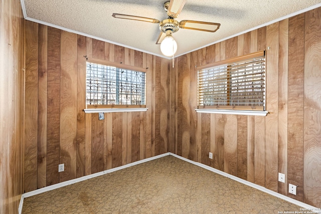 empty room featuring ceiling fan, wooden walls, and a textured ceiling