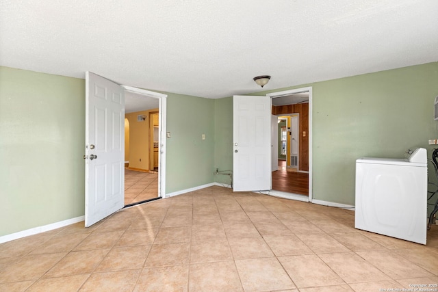 interior space with light tile patterned floors, washer / dryer, and baseboards