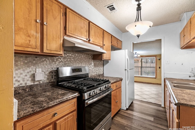 kitchen with dark countertops, visible vents, stainless steel range with gas stovetop, a textured ceiling, and under cabinet range hood