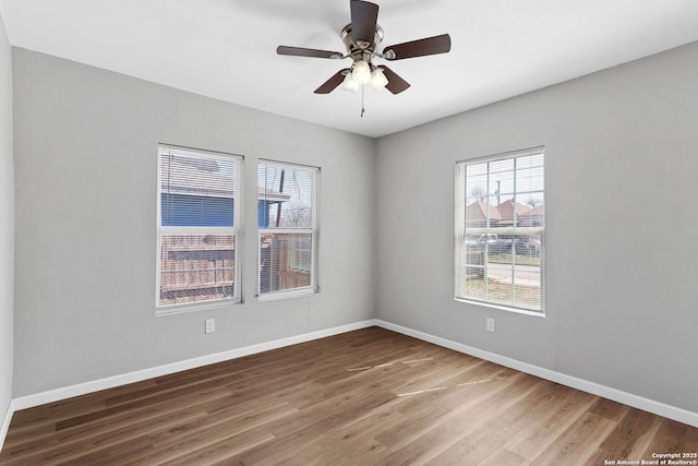 unfurnished room featuring a ceiling fan, baseboards, and wood finished floors