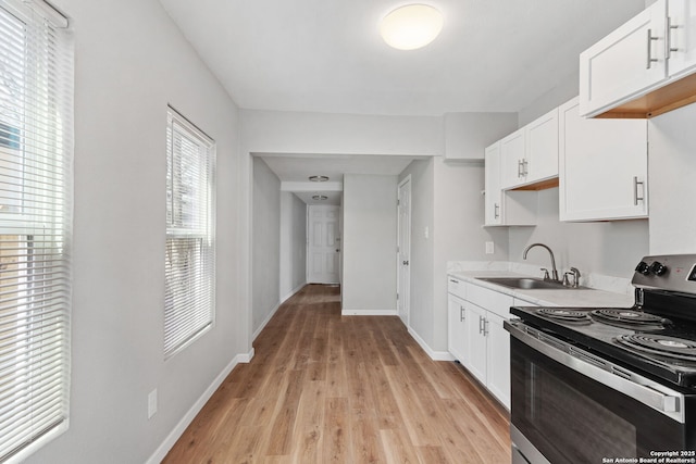 kitchen featuring a sink, white cabinetry, stainless steel range with electric cooktop, light countertops, and light wood-type flooring