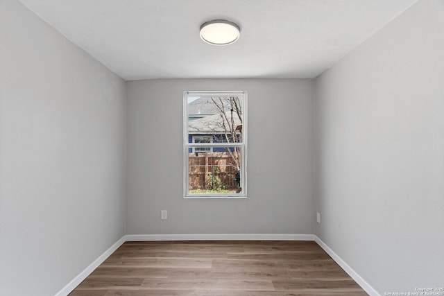 spare room with baseboards, wood finished floors, and a healthy amount of sunlight