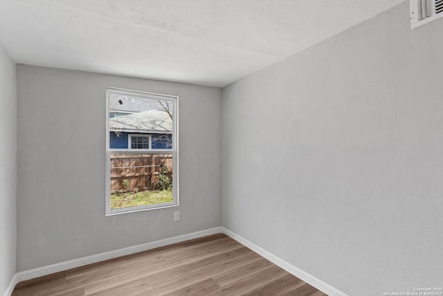 spare room featuring baseboards and wood finished floors