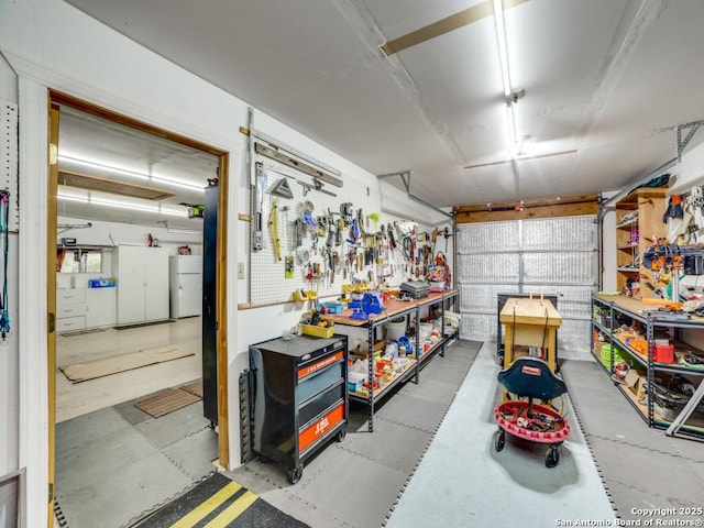 garage featuring a workshop area and freestanding refrigerator