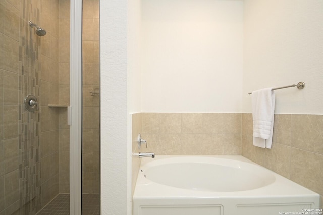 bathroom featuring a stall shower and a garden tub