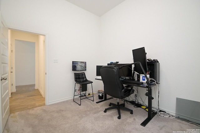 carpeted office space with vaulted ceiling and baseboards