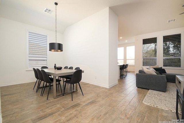 dining area with visible vents, baseboards, lofted ceiling, and wood finished floors