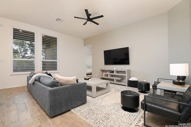 living area with light wood finished floors, visible vents, baseboards, and a ceiling fan