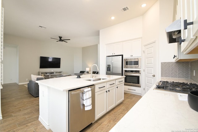 kitchen featuring a sink, visible vents, appliances with stainless steel finishes, decorative backsplash, and light wood finished floors