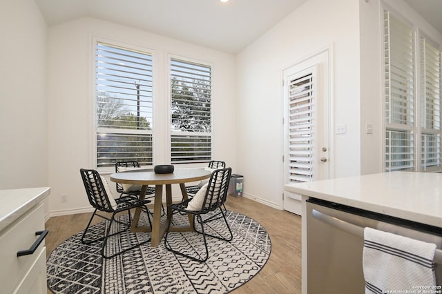 dining space with lofted ceiling, light wood-type flooring, and baseboards