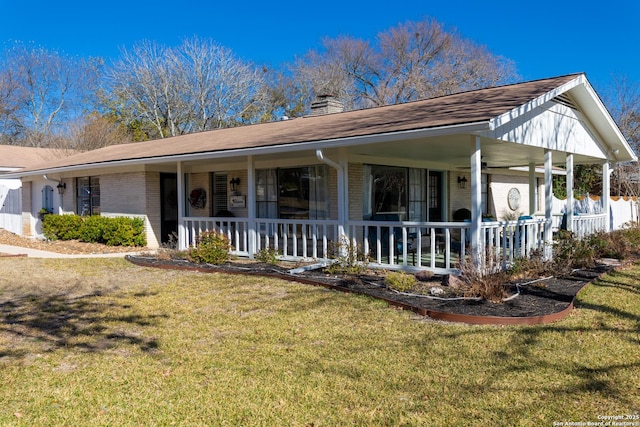 view of front of house featuring a front yard, a chimney, a porch, and brick siding