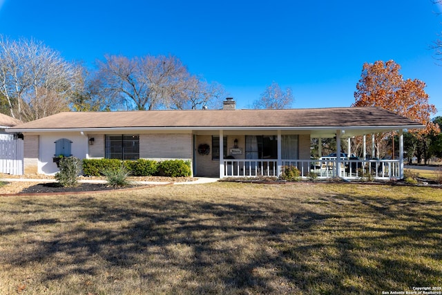 view of front of home featuring a chimney, brick siding, a porch, and a front yard