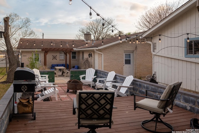 wooden deck with a fire pit and a pergola