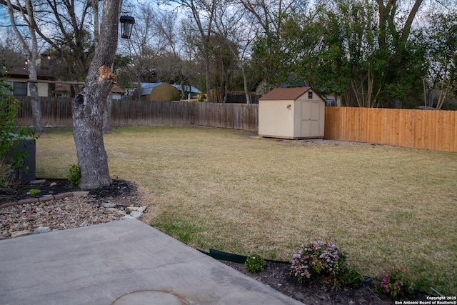 view of yard featuring a storage shed, a fenced backyard, and an outbuilding