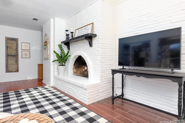 living room with wood finish floors, visible vents, a fireplace, and baseboards