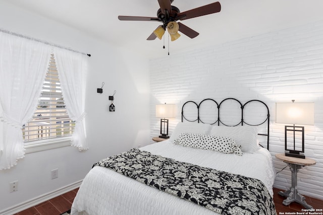 bedroom featuring a ceiling fan, brick wall, baseboards, and wood finished floors