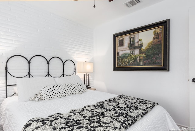 bedroom featuring visible vents, ceiling fan, and brick wall