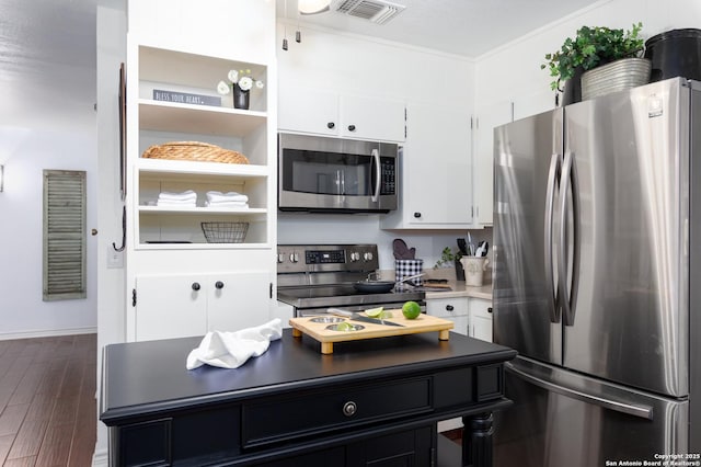 kitchen featuring visible vents, white cabinets, appliances with stainless steel finishes, dark wood-style flooring, and crown molding