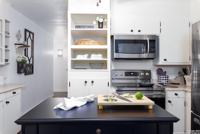 kitchen featuring stainless steel appliances, a kitchen island, white cabinets, open shelves, and dark countertops