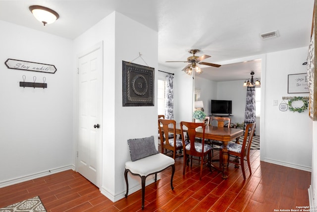 dining space featuring ceiling fan with notable chandelier, baseboards, visible vents, and wood tiled floor