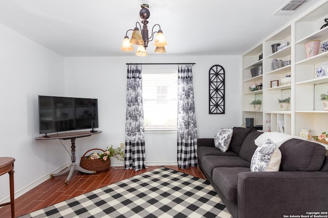 living room with wood finish floors, visible vents, a notable chandelier, and baseboards