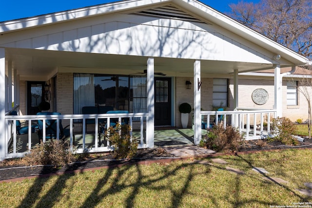 exterior space featuring covered porch, brick siding, and a yard