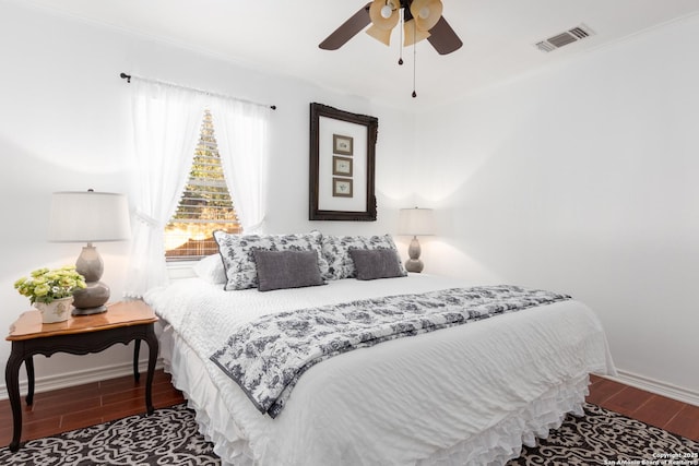 bedroom featuring a ceiling fan, visible vents, baseboards, and wood finished floors