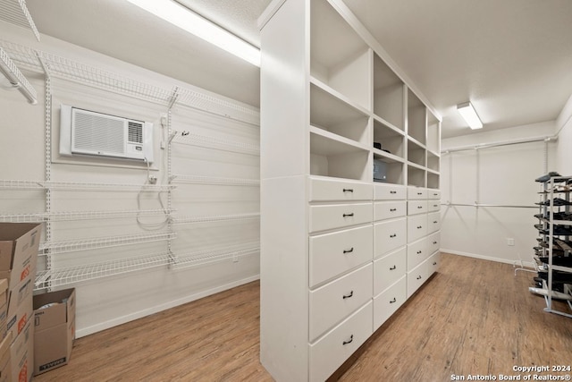 walk in closet featuring an AC wall unit and wood finished floors