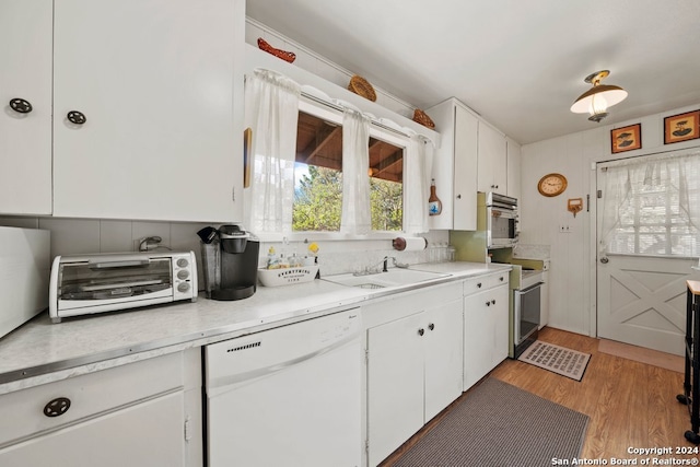 kitchen with white appliances, a sink, white cabinetry, and a toaster