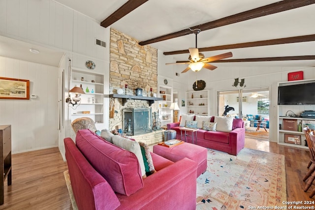 living area with visible vents, ceiling fan, a stone fireplace, and wood finished floors