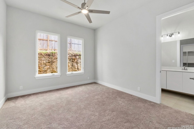 unfurnished bedroom featuring light colored carpet, a sink, and baseboards